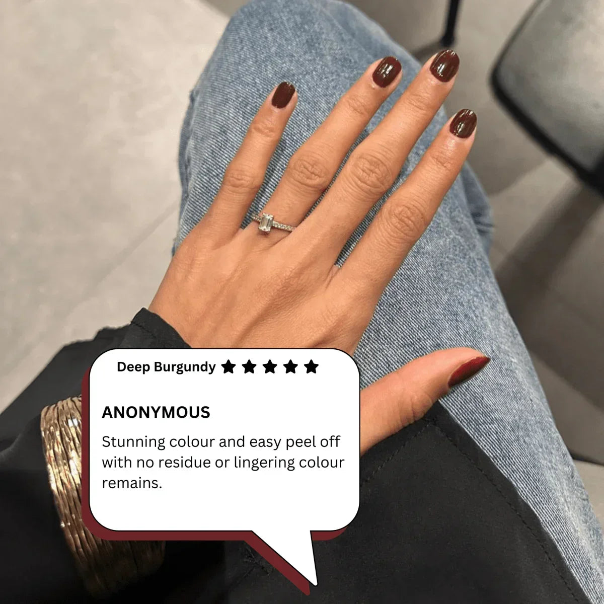 Hand with deep burgundy peelable nail polish, wearing a ring, peelanails review visible.